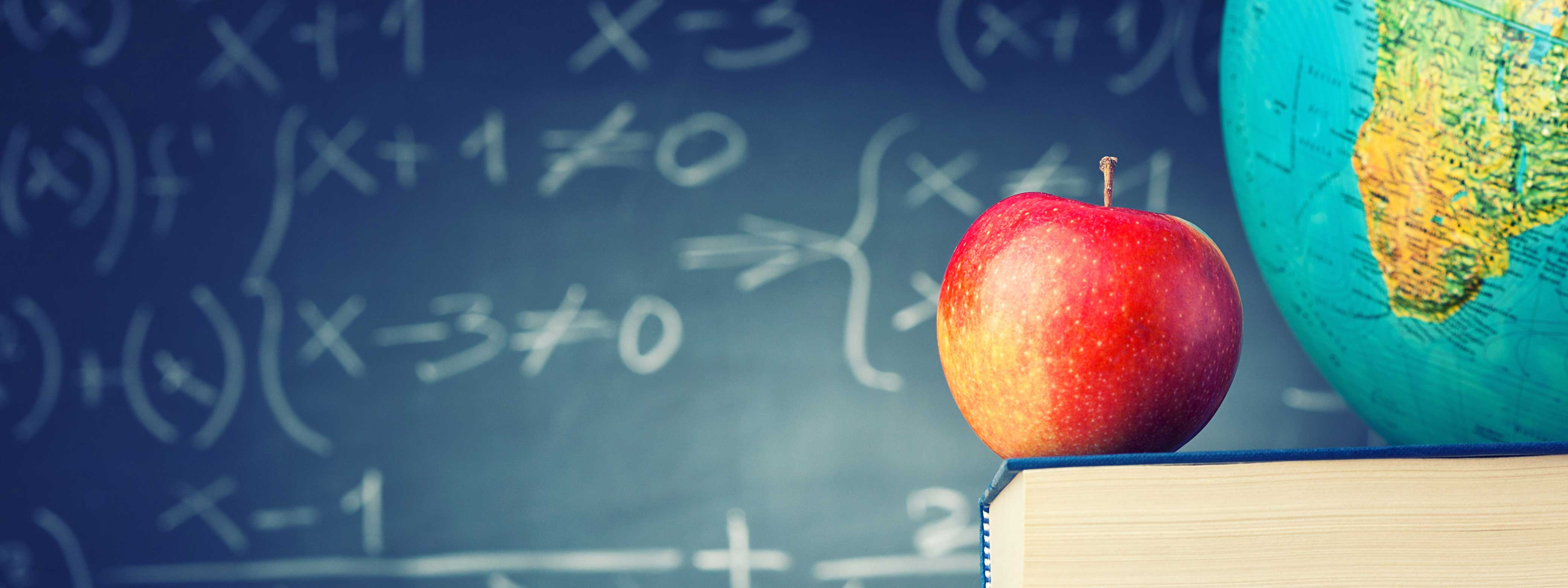 math formula on chalkboard with apple book and globe